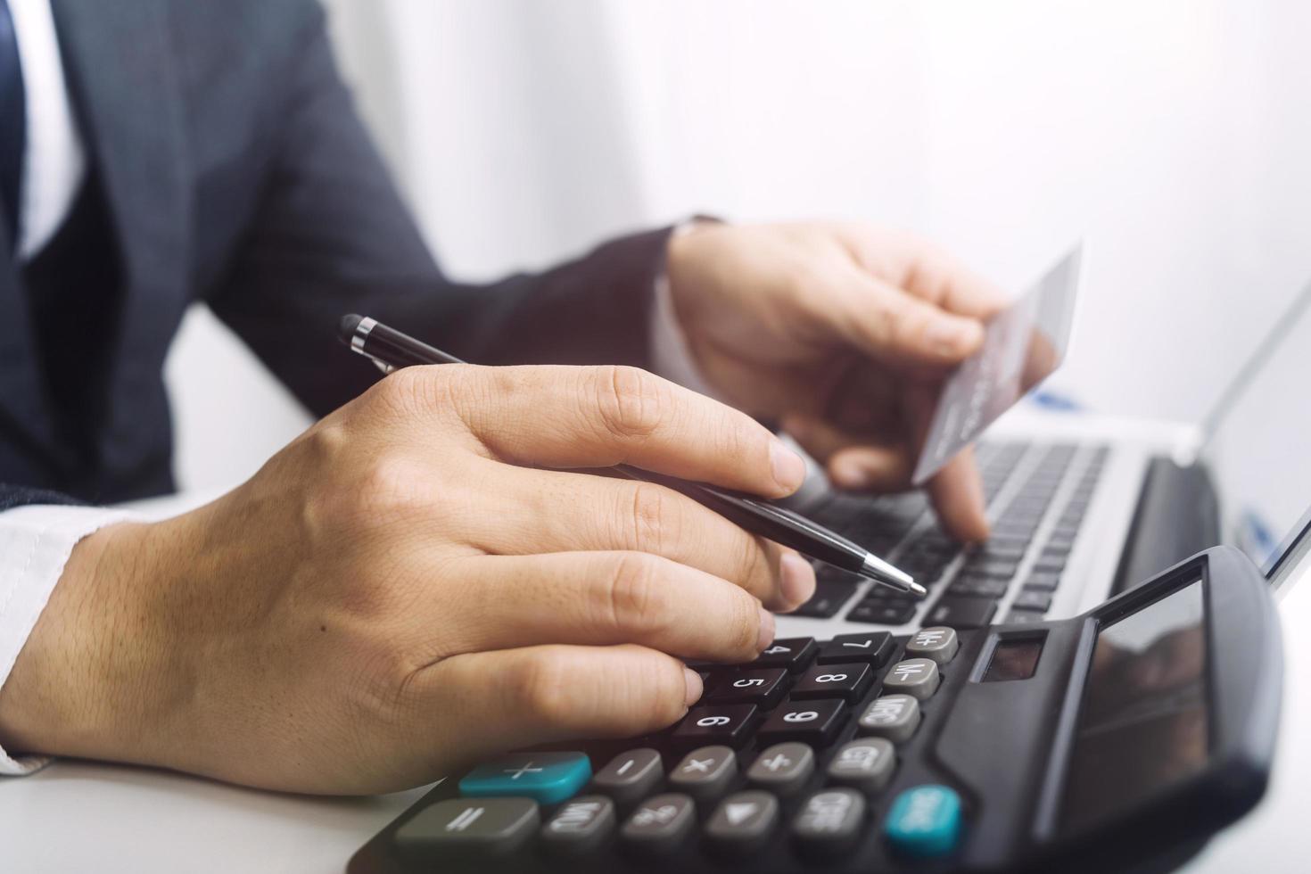 Woman entrepreneur using a calculator with a pen in her hand, calculating financial expense at home office photo