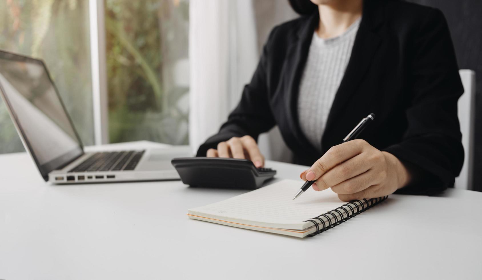 Woman entrepreneur using a calculator with a pen in her hand, calculating financial expense at home office photo
