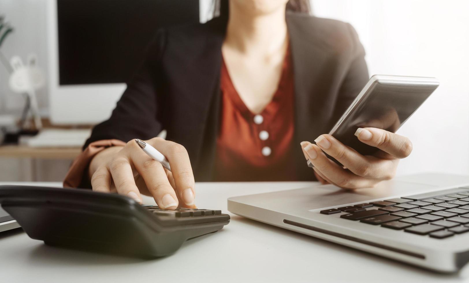 Woman entrepreneur using a calculator with a pen in her hand, calculating financial expense at home office photo