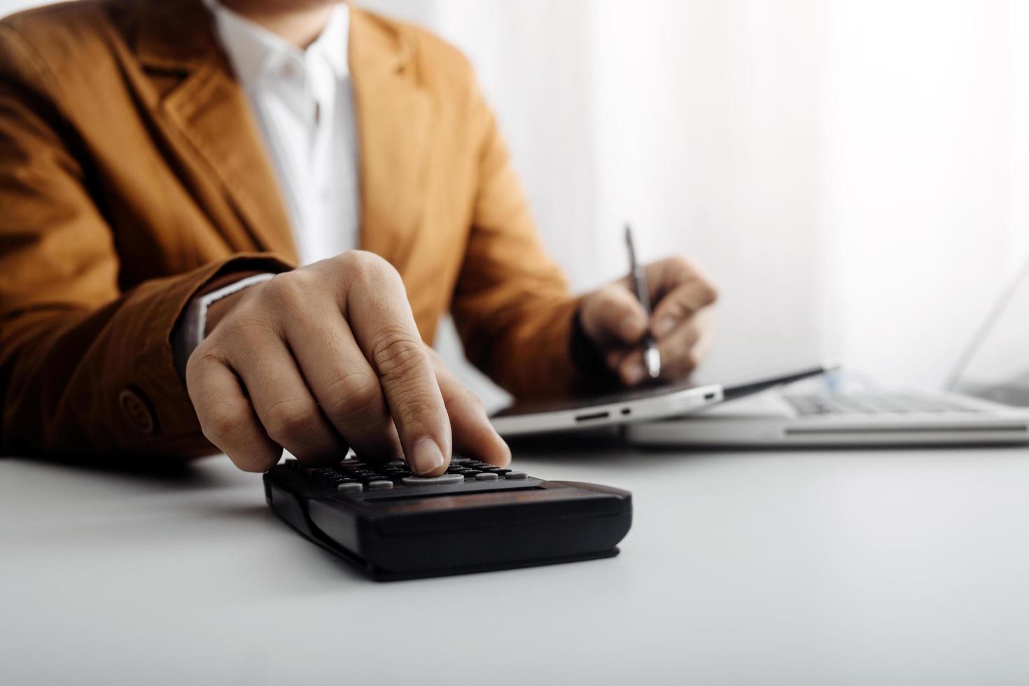 Woman entrepreneur using a calculator with a pen in her hand, calculating financial expense at home office photo