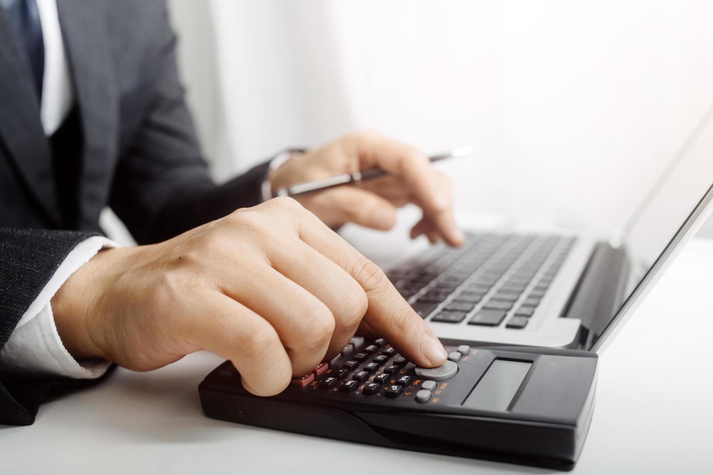 Woman entrepreneur using a calculator with a pen in her hand, calculating financial expense at home office photo