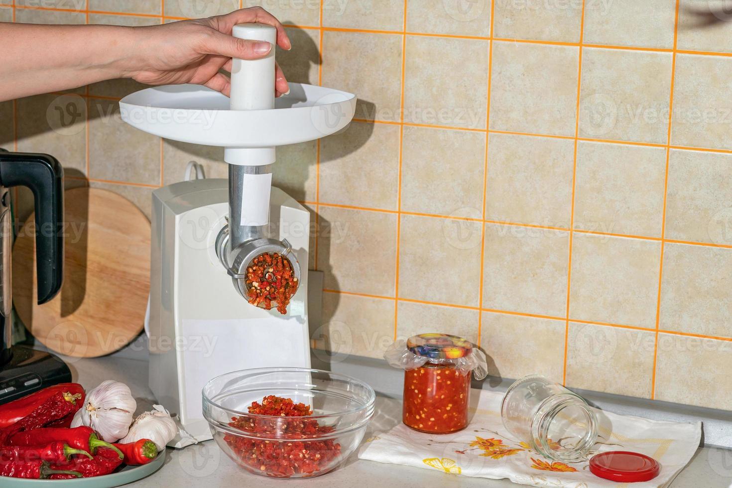cooking adjika from hot pepper and garlic ground in a meat grinder. preparations for the winter. folk remedy for flu and colds photo