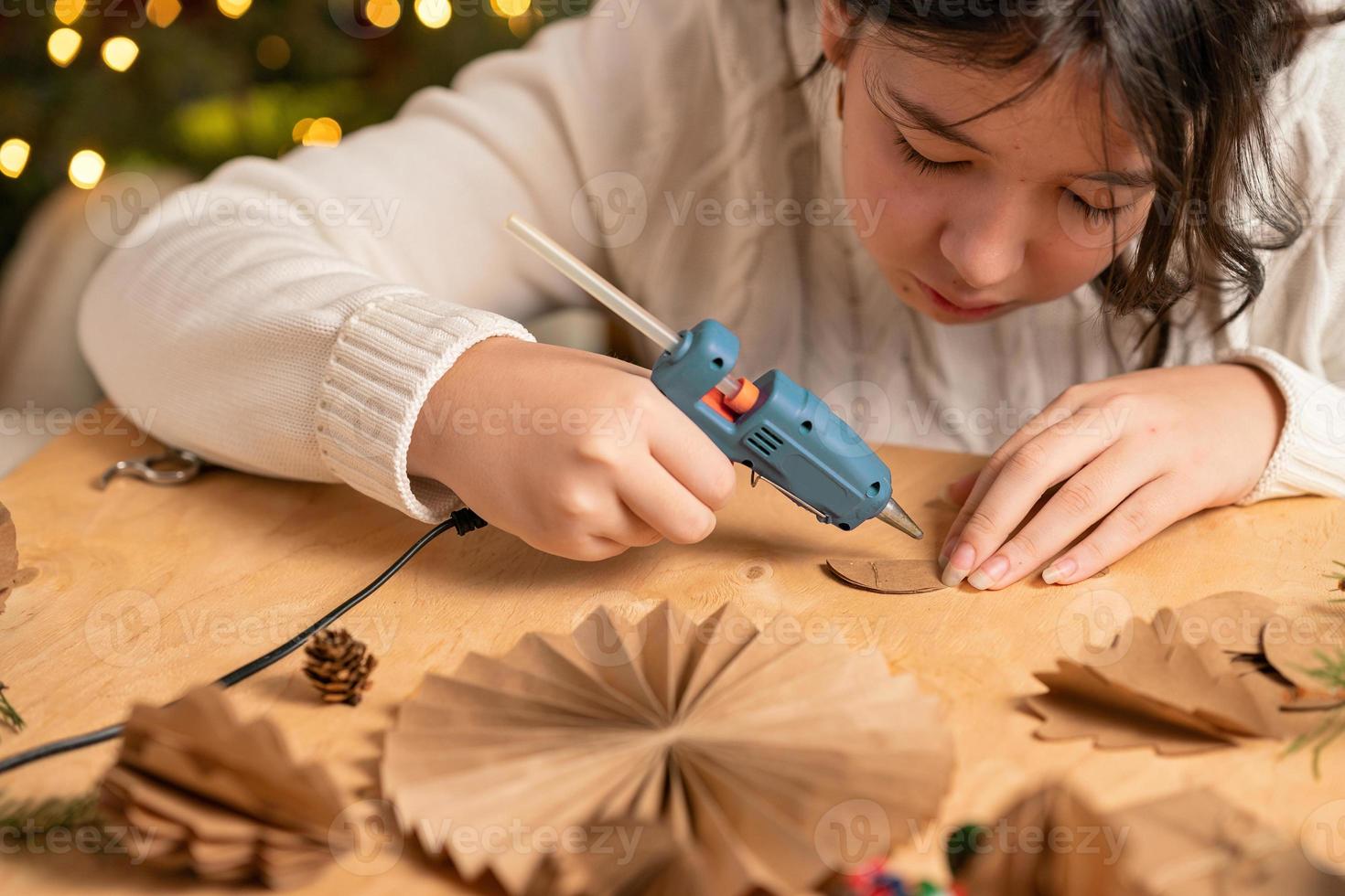 girl makes Christmas tree decorations out of paper with her own hands. step 3. step-by-step instruction photo