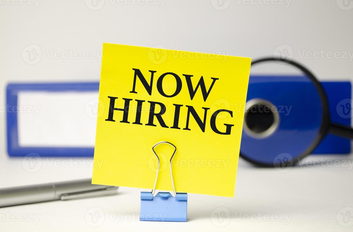 Now Hiring word on notepad with glasses and chart photo