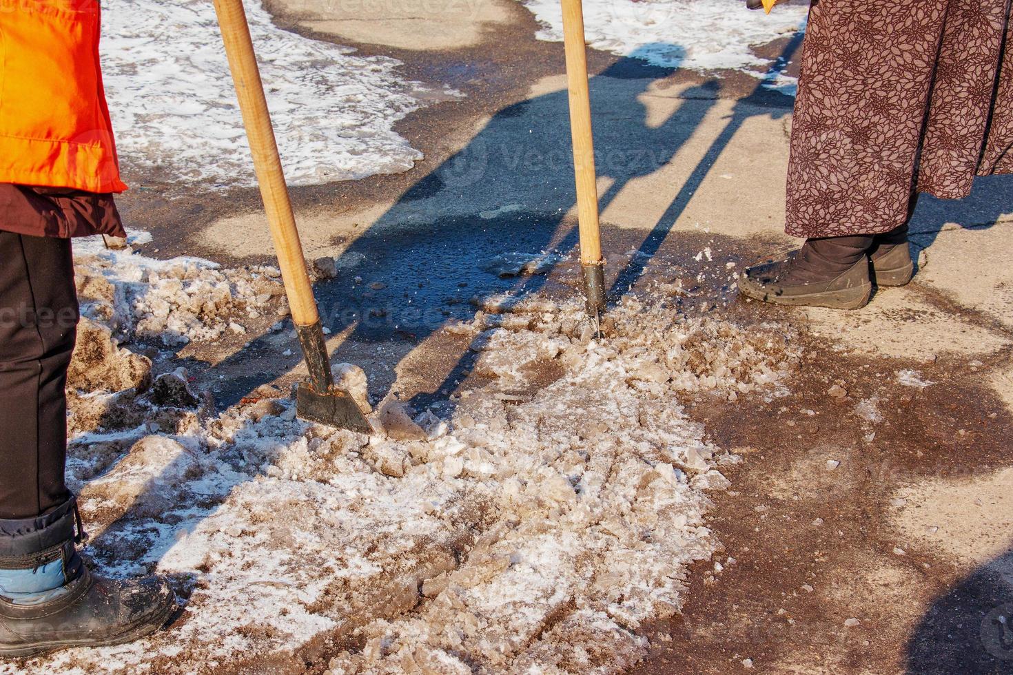 A woman worker cleans the ice and removes snow from paving slabs using an icebreaker. photo