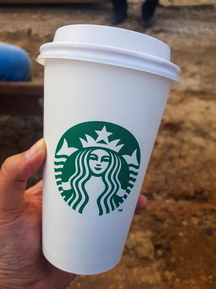 yakarta, indonesia en julio de 2021. una mano sostiene una taza de café starbucks foto