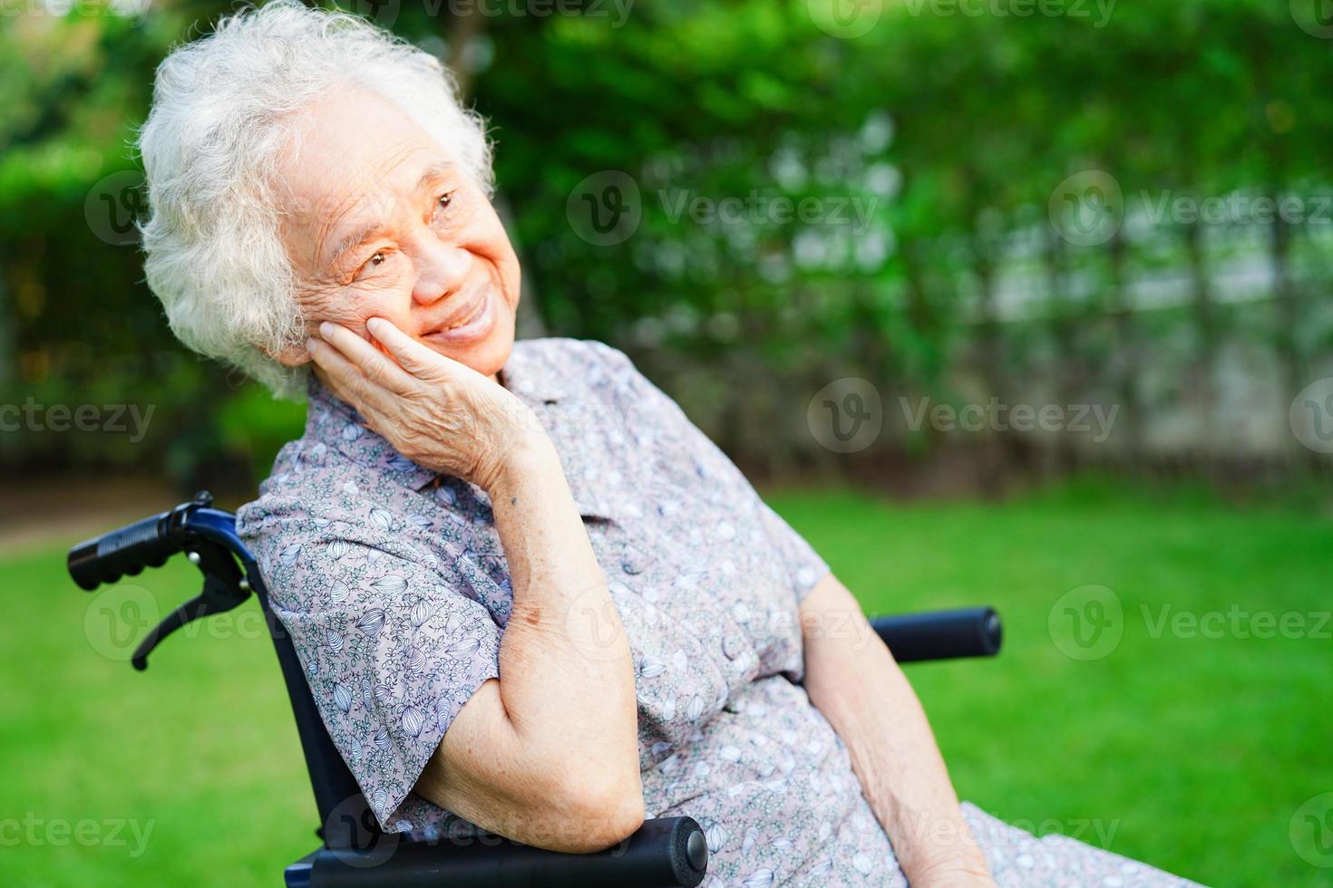 Asian elderly woman disability patient sitting on wheelchair in park, medical concept. photo