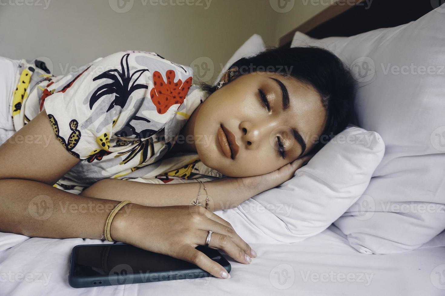 mujer joven y atractiva durmiendo en el dormitorio, está acostada a un lado y relajándose con los ojos cerrados foto