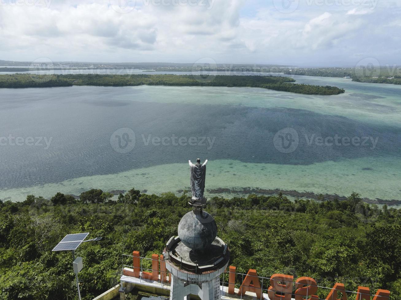 vista aérea de la estatua de jesús con hermosa vista a la playa en una pequeña isla. maluku, indonesia - julio, 2022 foto