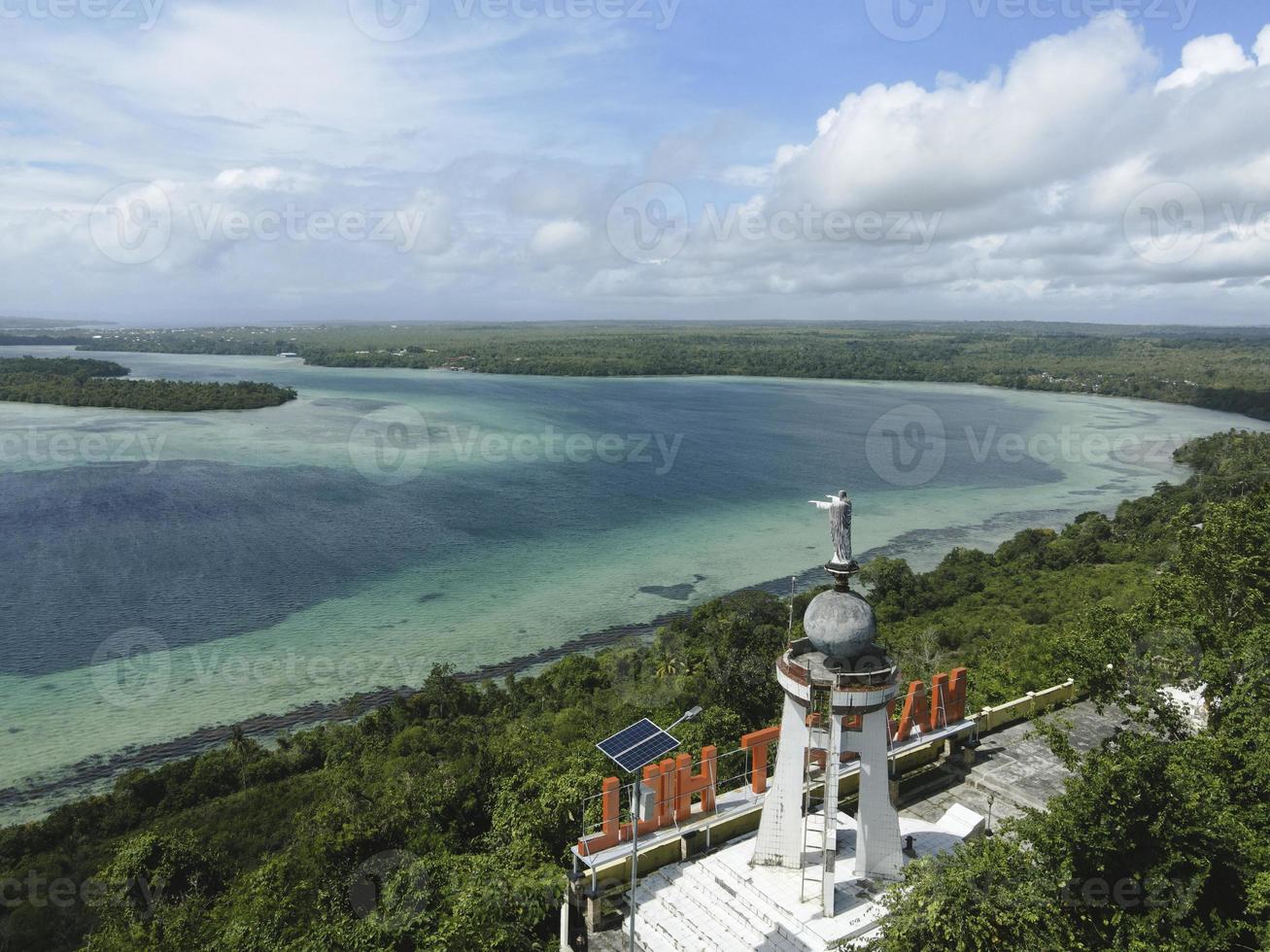 Aerial view of Jesus statue with beautiful beach view in small island. Maluku, Indonesia - July, 2022 photo
