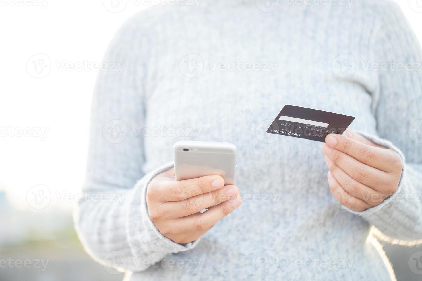 A woman using a credit card to pay for goods online with a mobile phone photo