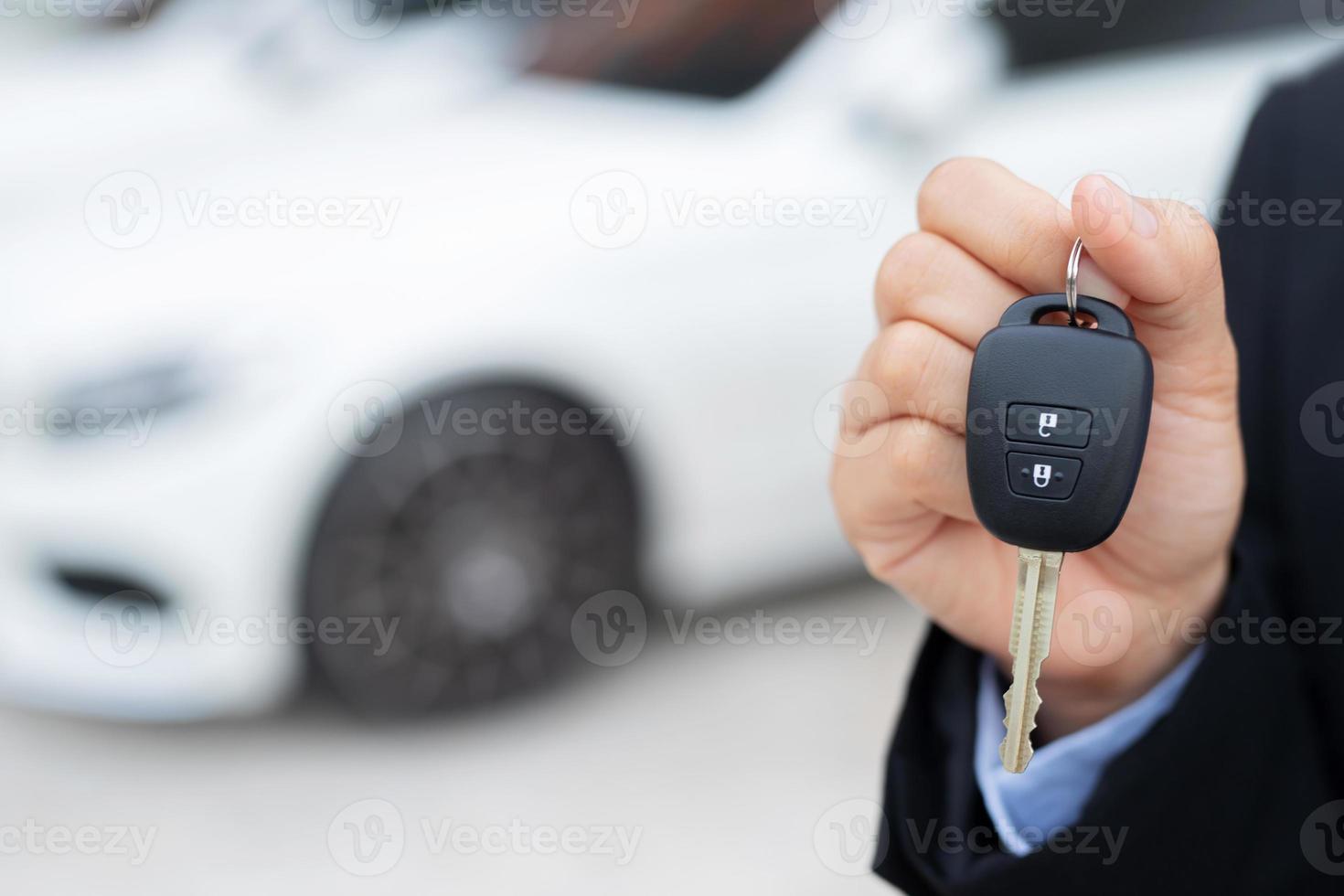 Salesman is carrying the car keys delivered to the customer at the showroom with a low interest offer. Special promotion photo