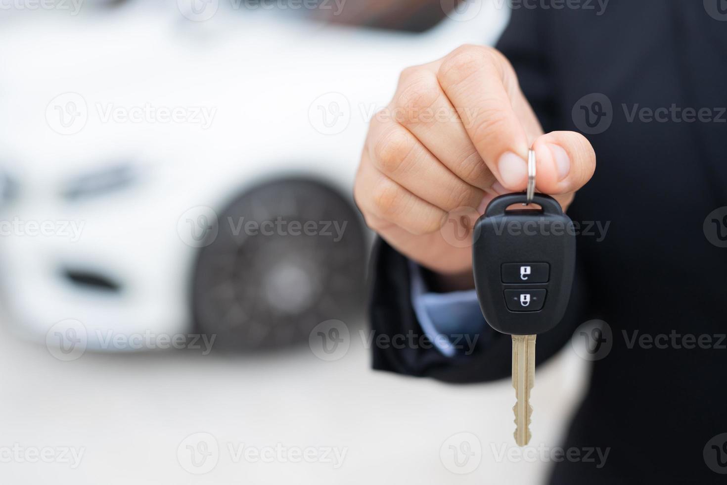 Salesman is carrying the car keys delivered to the customer at the showroom with a low interest offer. Special promotion photo