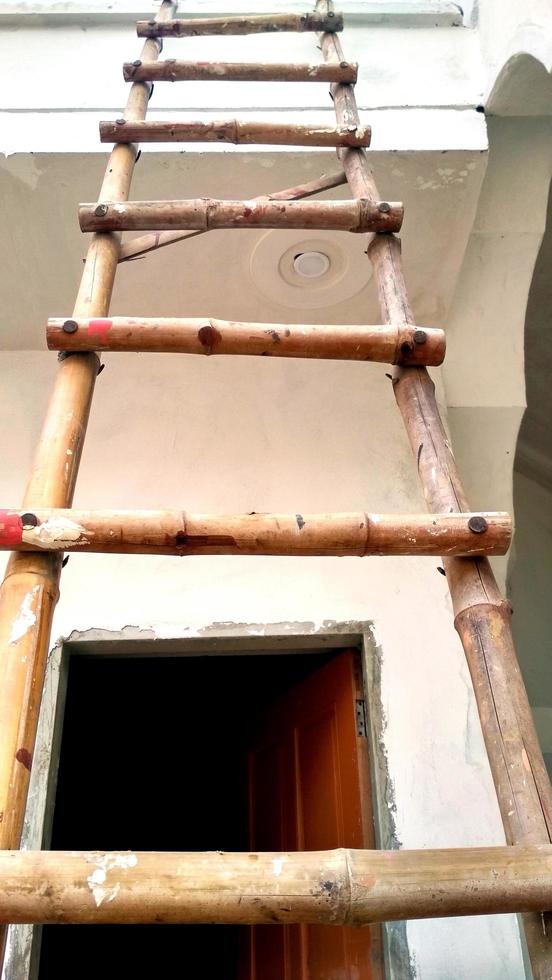 An old building with damaged facade with wooden ladder by the wall photo