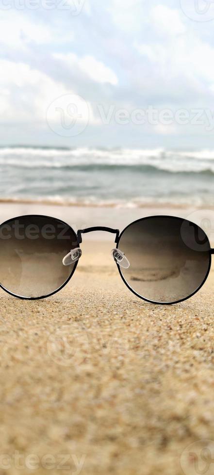 Sun glasses at the sand of the beach near the sea photo