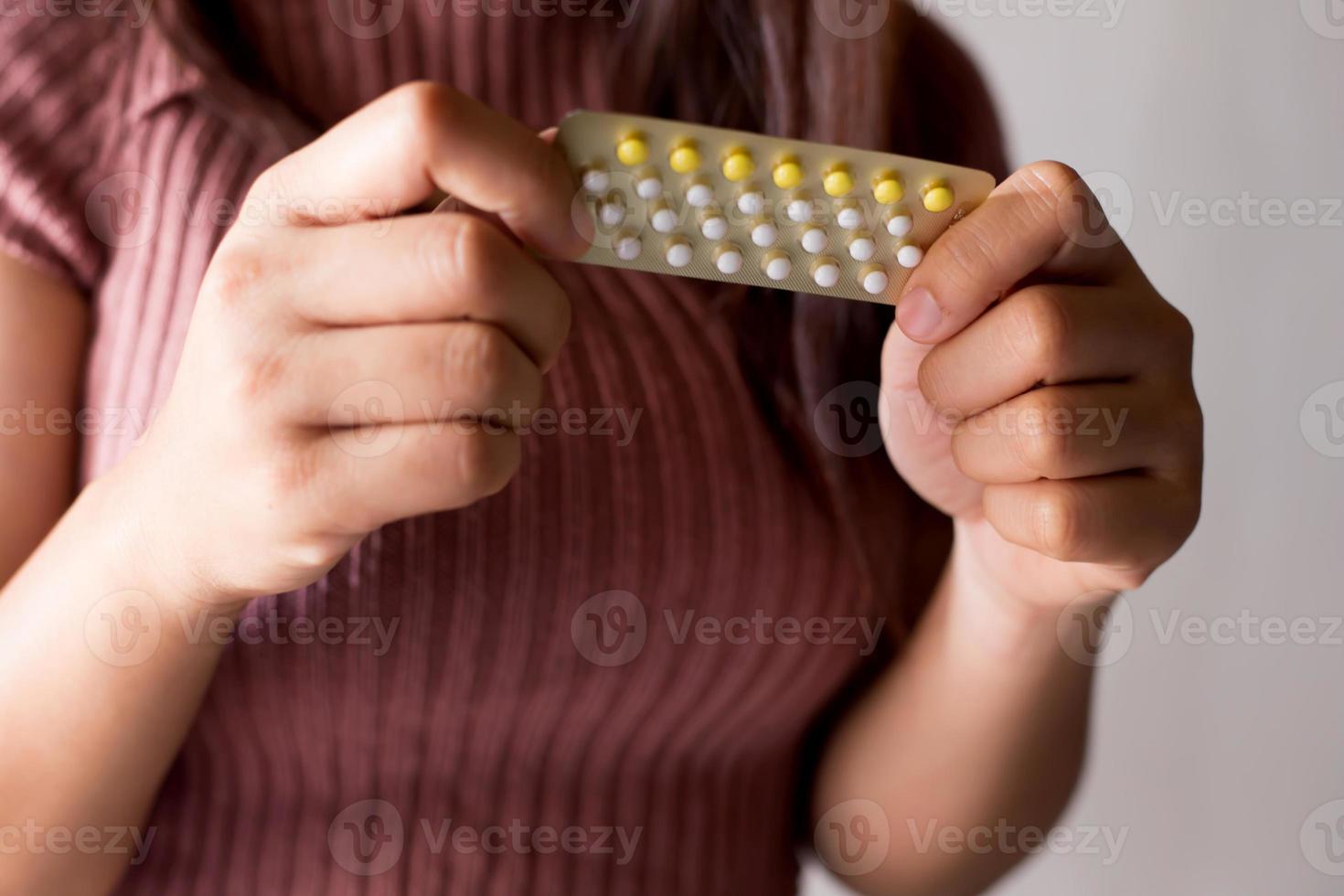 Women holding birth control pills, focus hand photo