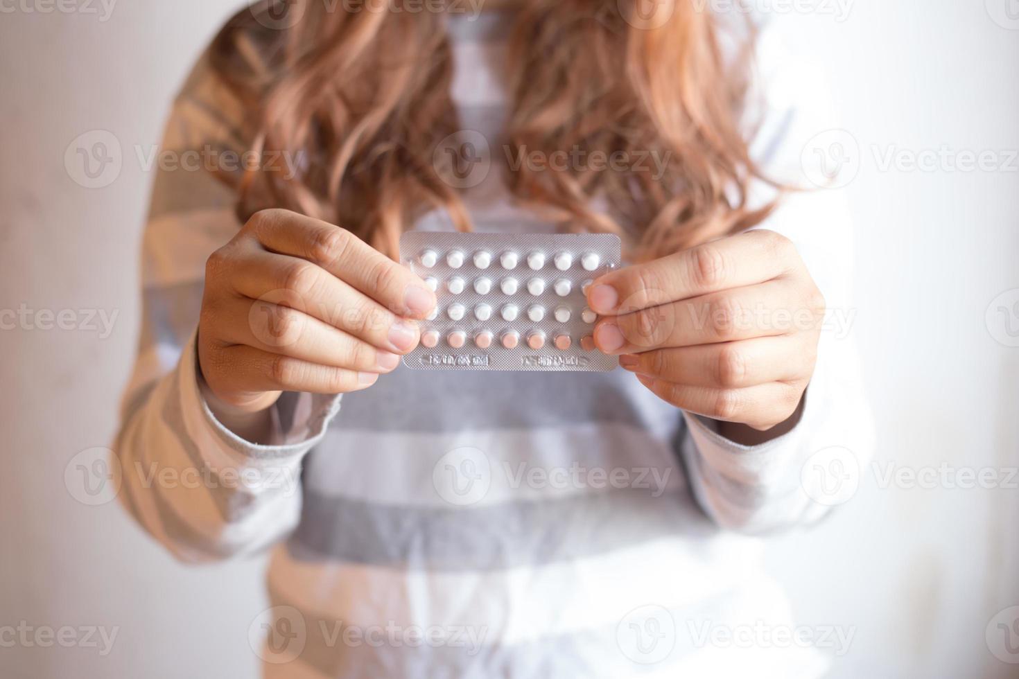 Women holding birth control pills, focus hand photo