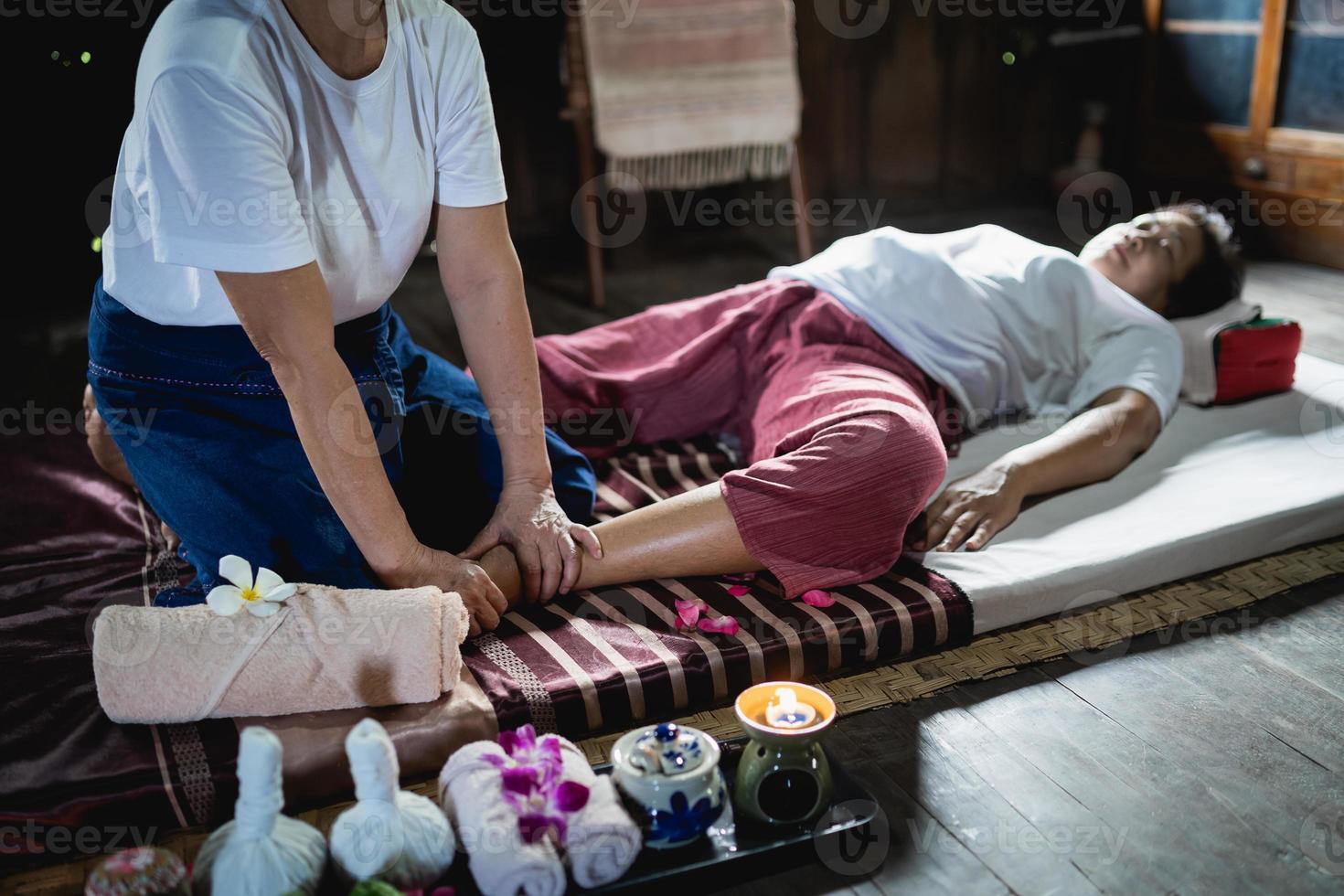 Foot massage and spa relaxing treatment of office syndrome traditional thai massage style. Asian senior female masseuse doing feet massage treat foot and stress for old woman tired. photo