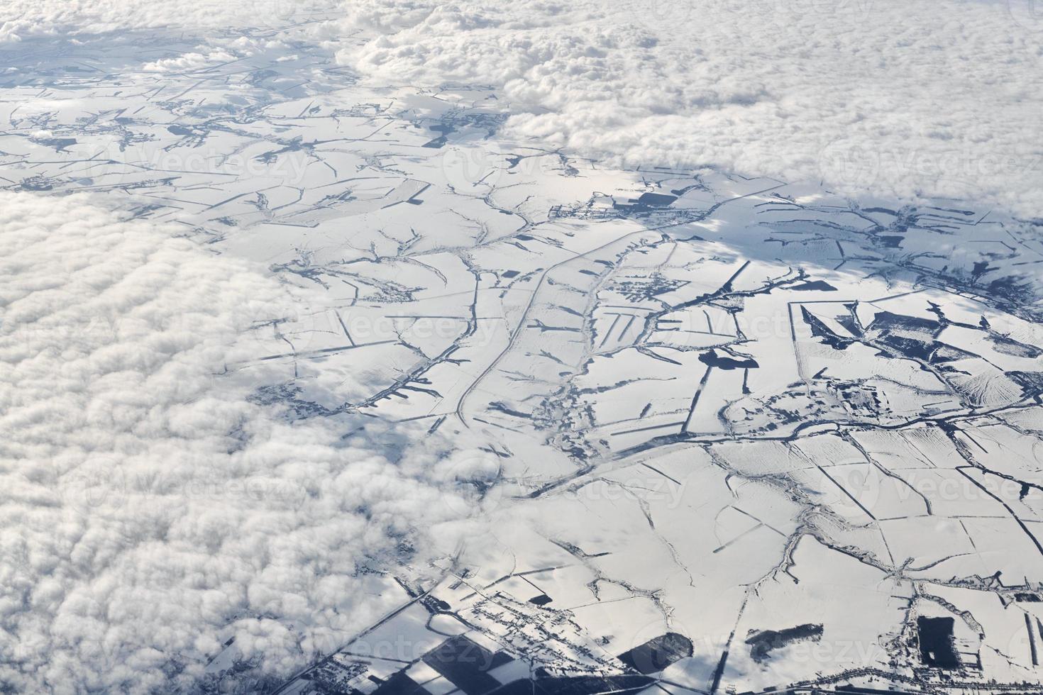 Aerial view over clouds top to snow covered rivers, fields and roads, winter fresh frosty air photo