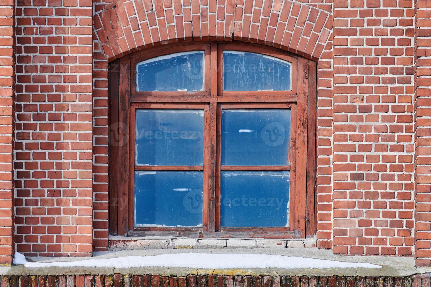 una ventana de cristal arqueada en la pared de ladrillo roja vieja foto