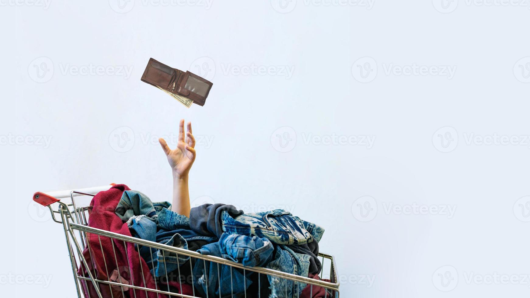 Shopaholic concept. Female hand sticks out of shopping cart photo