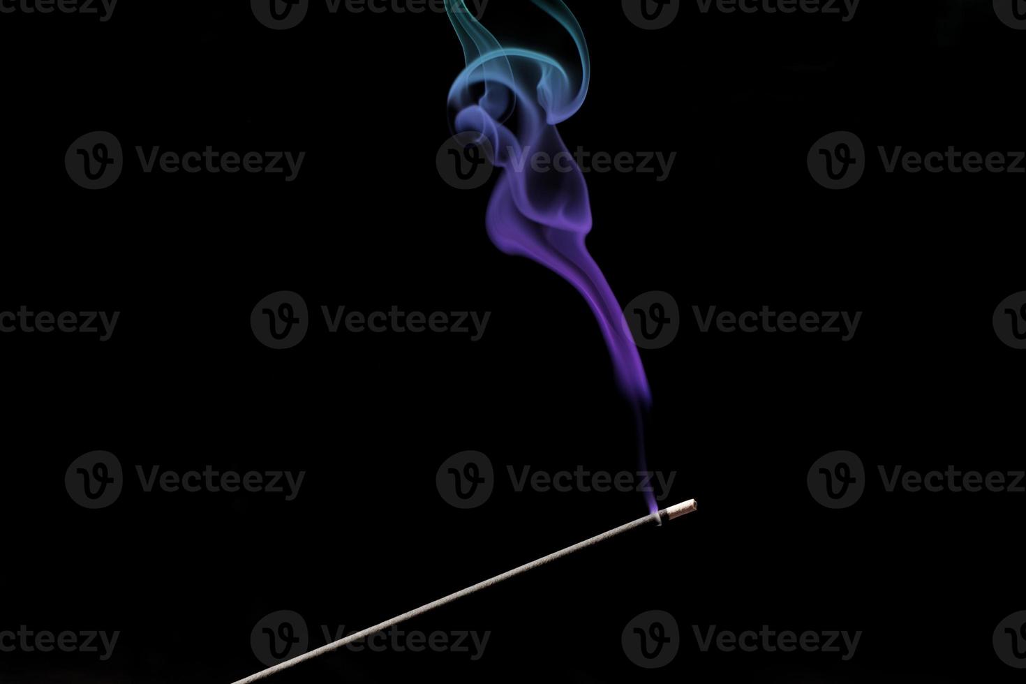 Smoke curls from burning incense stick for relaxation and meditation black background photo