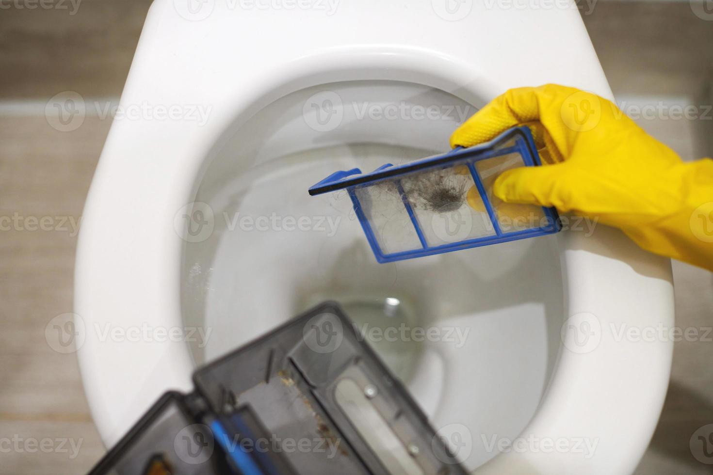 Hands in rubber gloves throw out trash in toilet, close up. photo