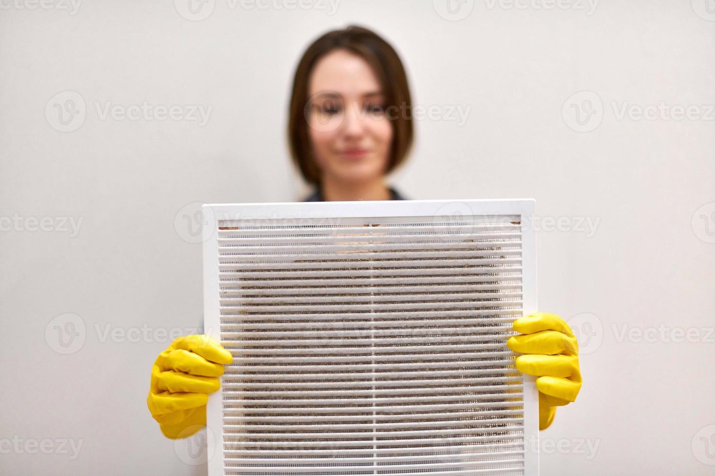 mujer sosteniendo una rejilla de ventilación sucia y polvorienta, borrosa. foto