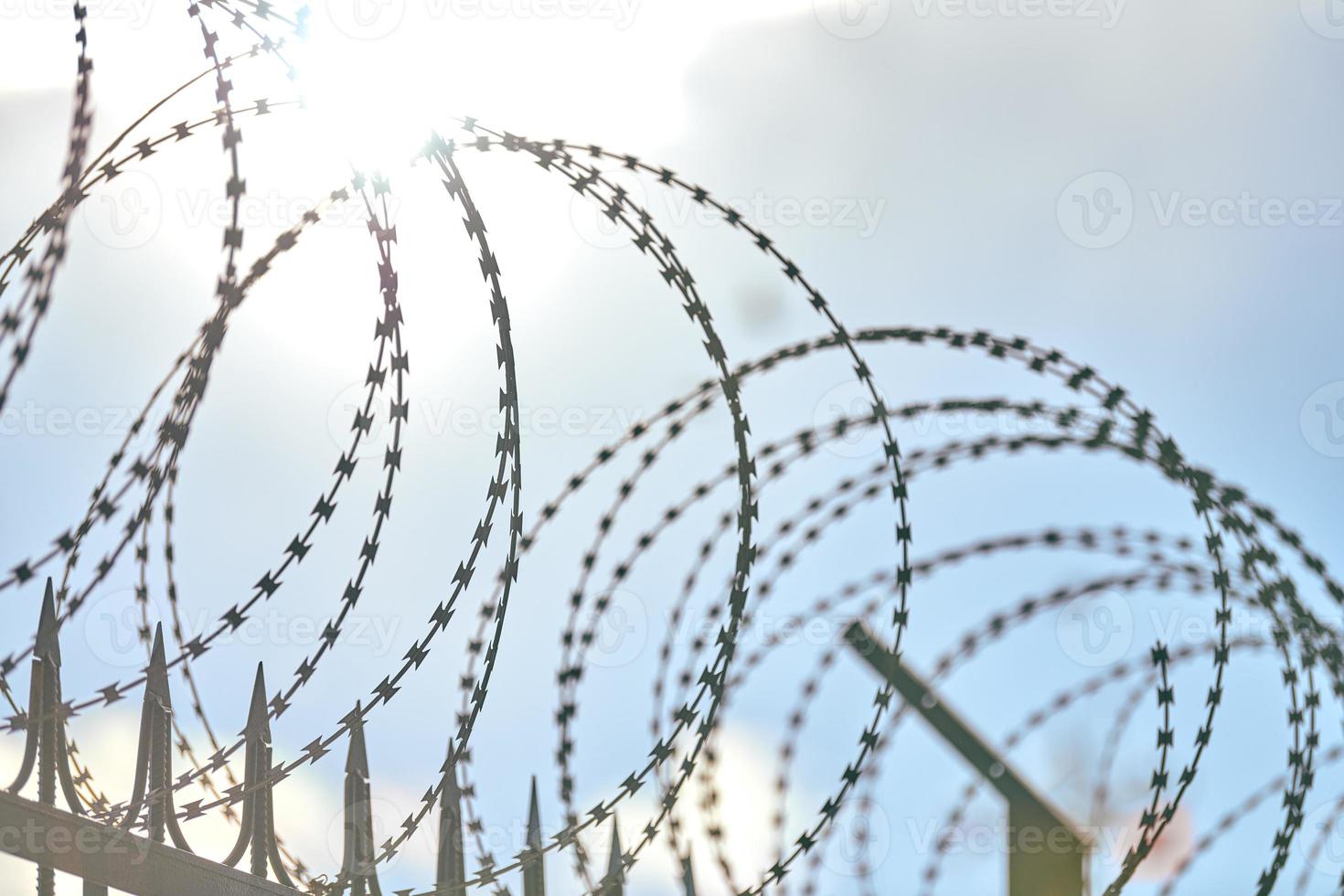 Barbed wire on fence, steel grating fence with barbs photo