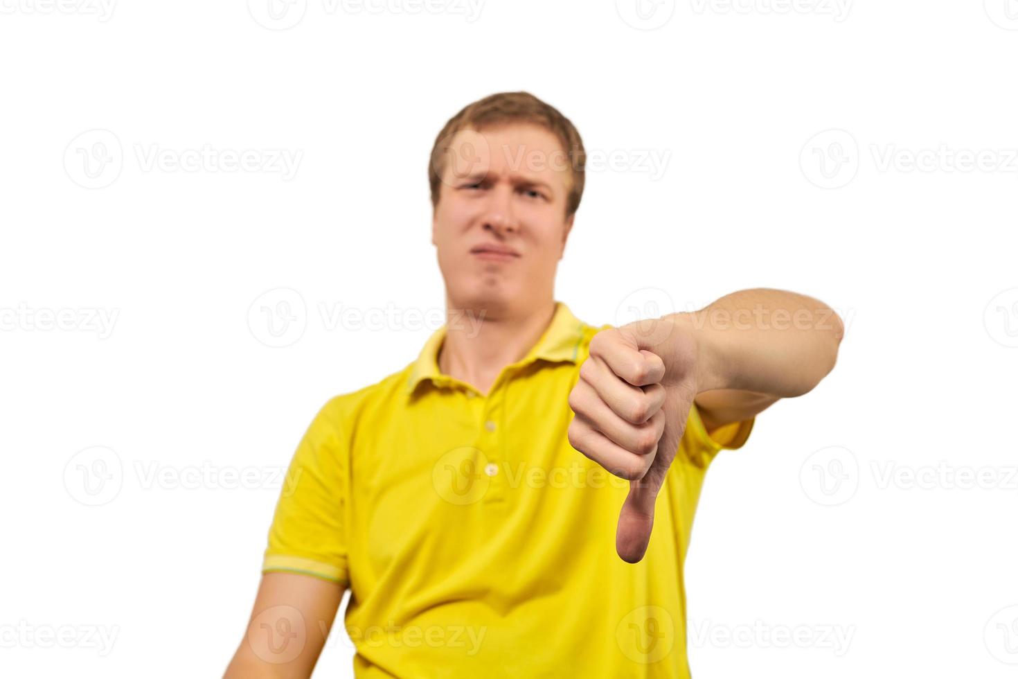 Unhappy annoyed man in yellow T-shirt showing thumbs down gesture isolated on white background photo