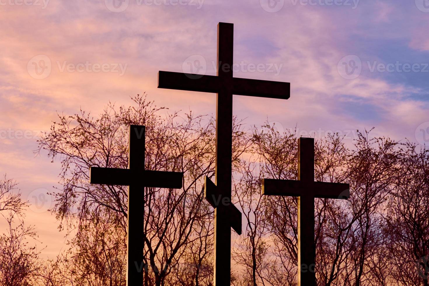 tres cruces en silueta al atardecer, cielo dramático foto