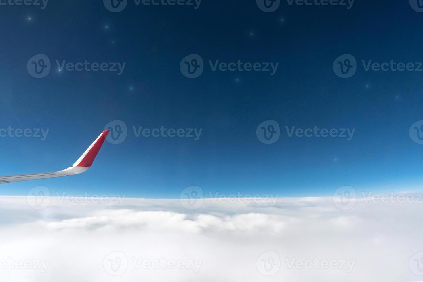 Airplane window view to cloudy sky and stars. Beautiful sky from aircraft cabin. Flying without incident and turbulence. photo
