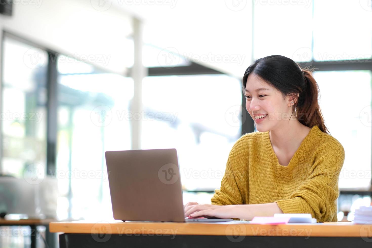 mujer de negocios asiática que usa una computadora portátil y trabaja en la oficina con un documento de calculadora en el escritorio, planificando el análisis del informe financiero, la inversión del plan de negocios, el concepto de análisis financiero. foto