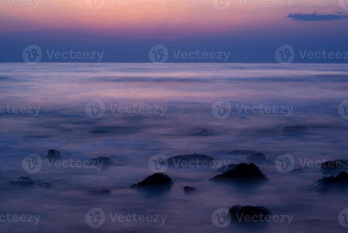 Soft waves on a rocky beach in the evening photo