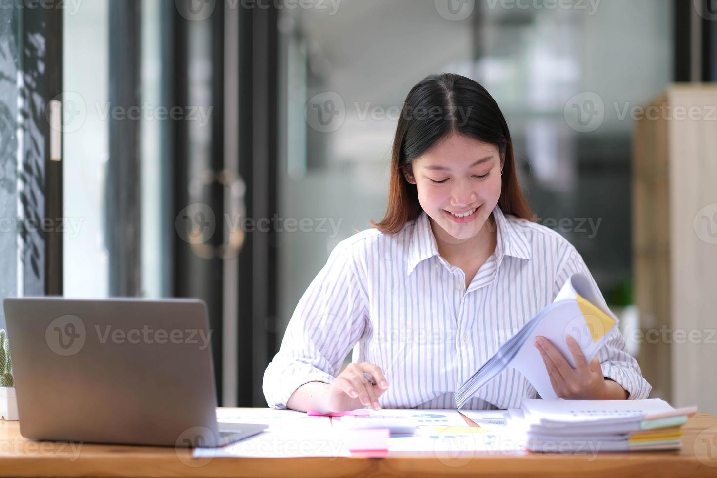 Pretty Asian woman sitting in the office, calculator, working on data, charts and documents on the table in business workspace. photo