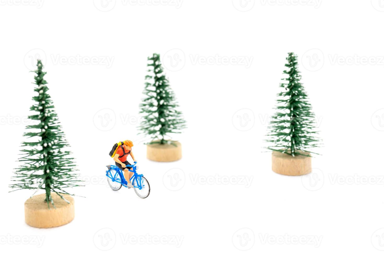Miniature people with gifts on a bicycle on white background photo