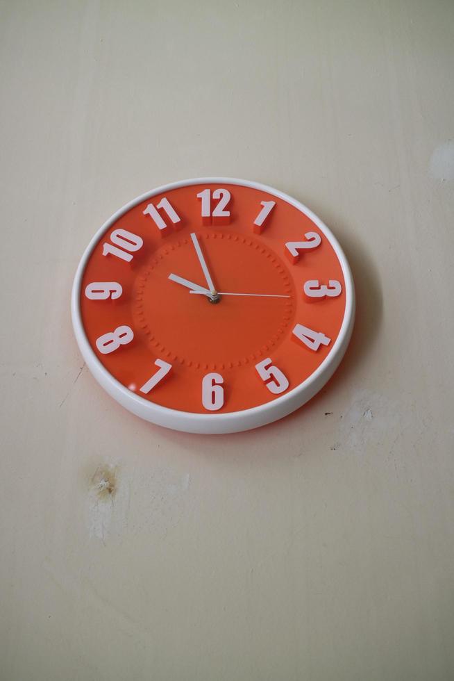 round orange wall clock with hands indicating 10 am photo
