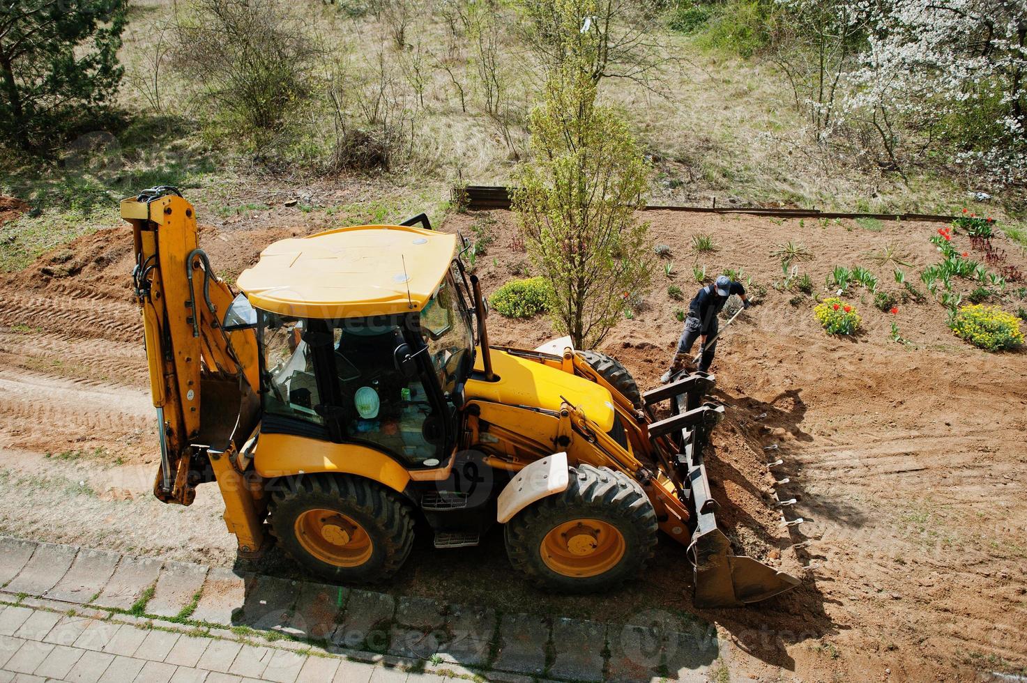 el cucharón del tractor nivela una zanja cerca de la casa foto