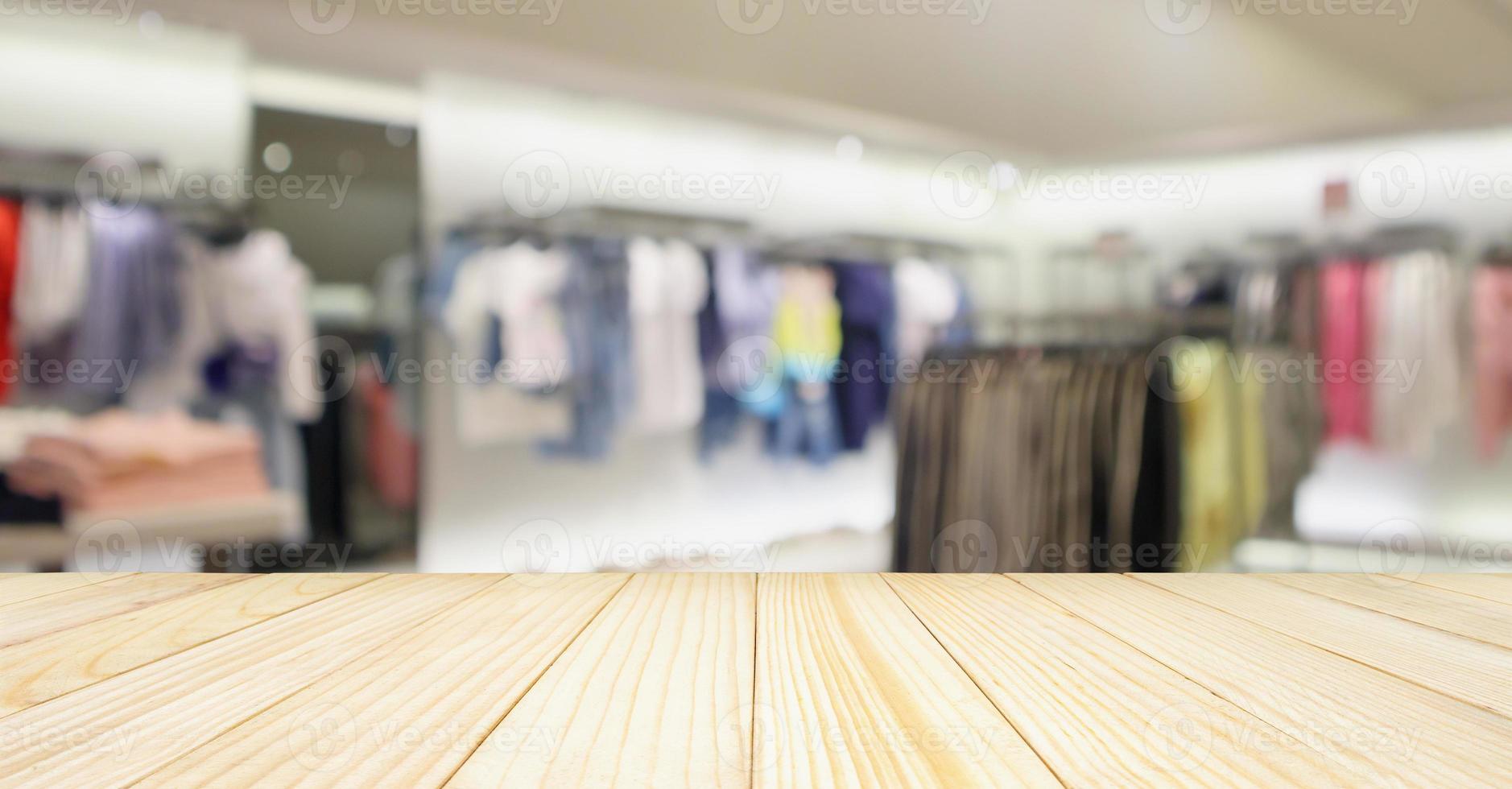 Empty wood table with woman fashionable boutique clothing store window display in shopping mall photo