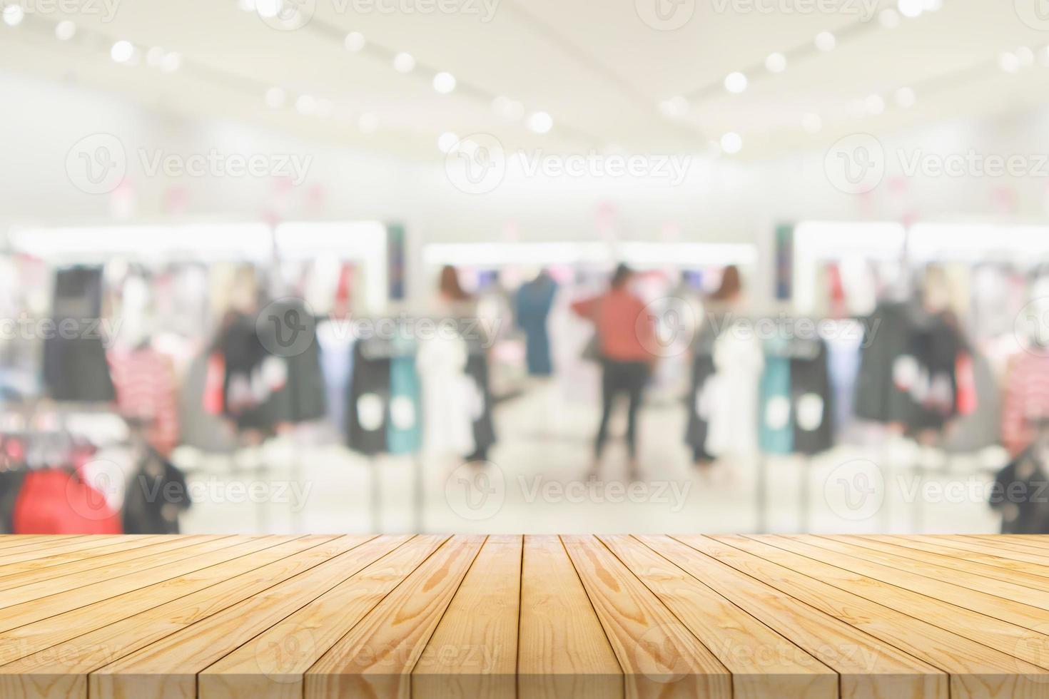 mesa de madera vacía con fondo de centro comercial interior de exhibición de boutique de ropa borrosa foto