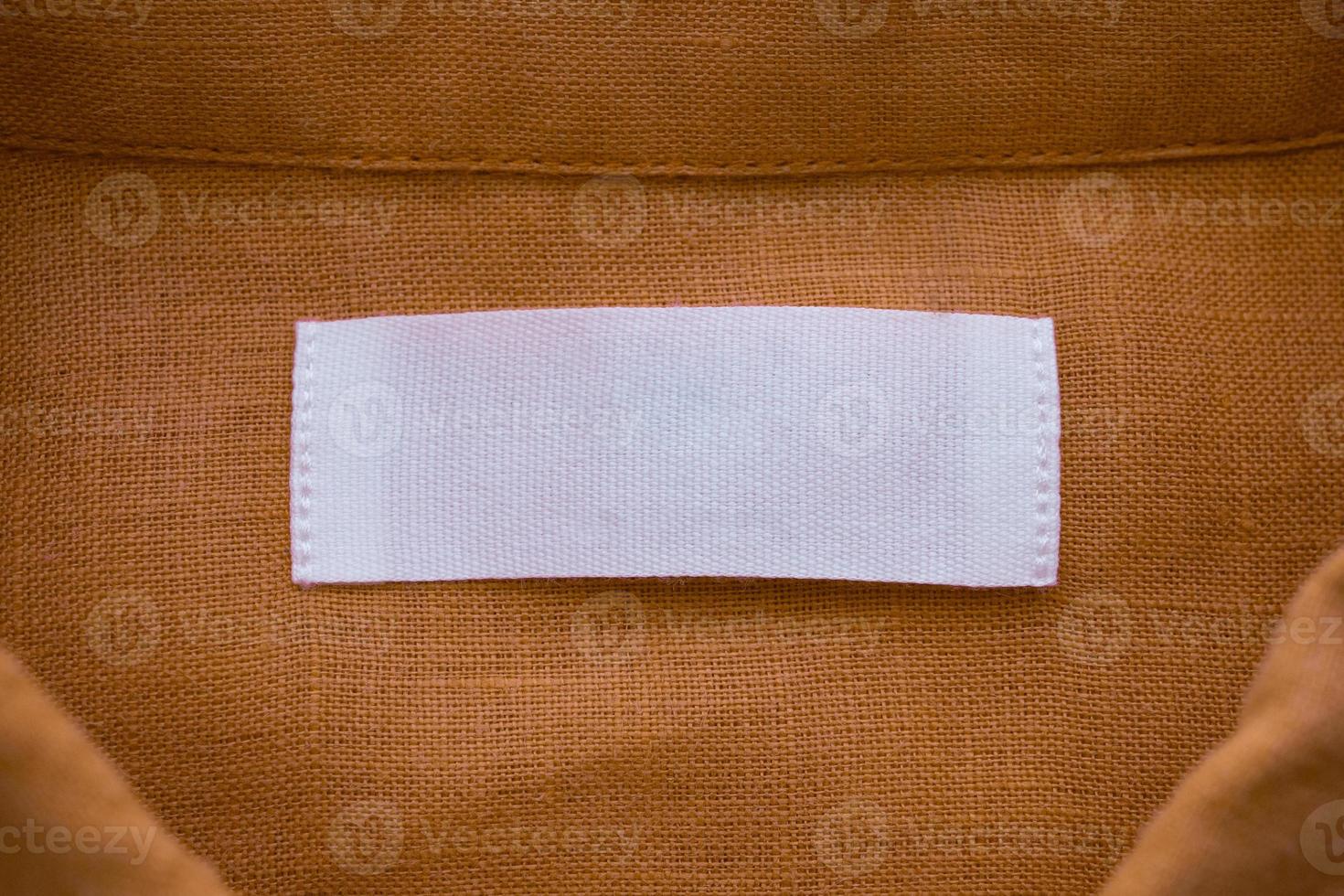 White blank clothing tag label on brown linen shirt fabric texture background photo