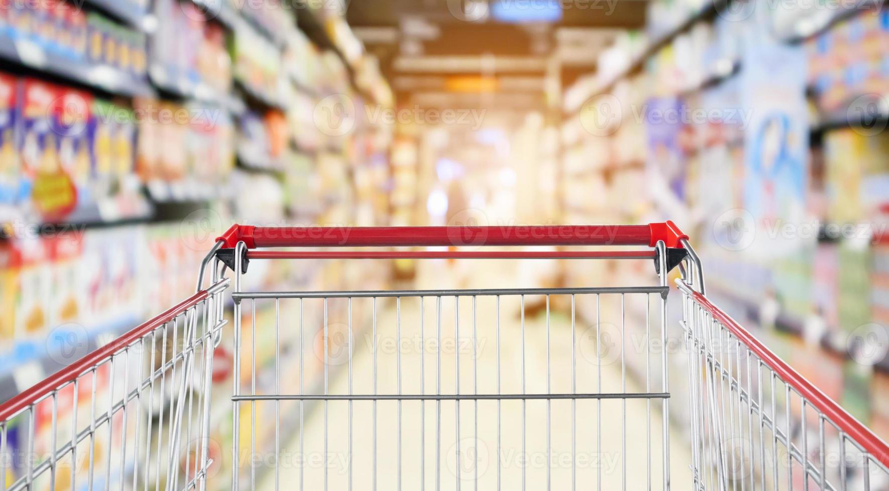 Empty shopping cart with abstract blur supermarket discount store aisle and product shelves interior defocused background photo