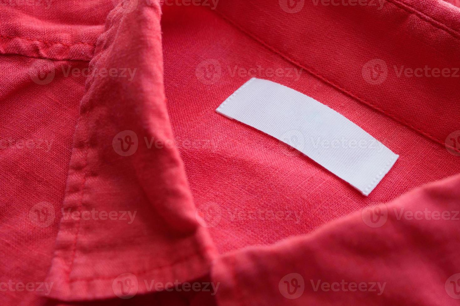 White blank clothing tag label on red linen shirt fabric texture background photo