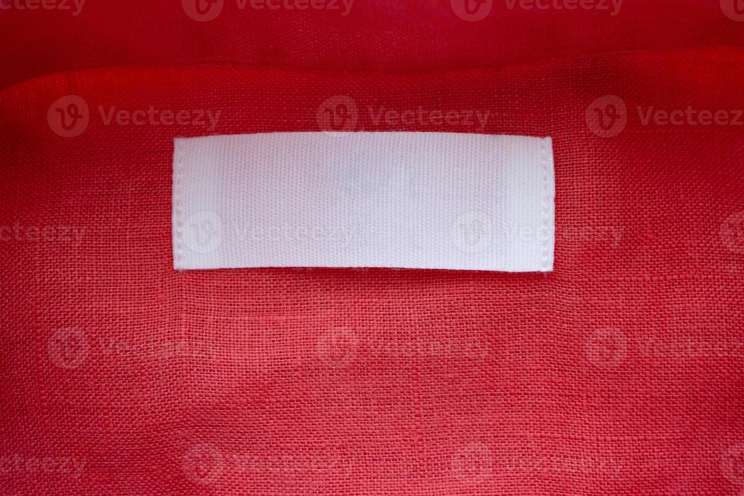 White blank clothing tag label on red linen shirt fabric texture background photo