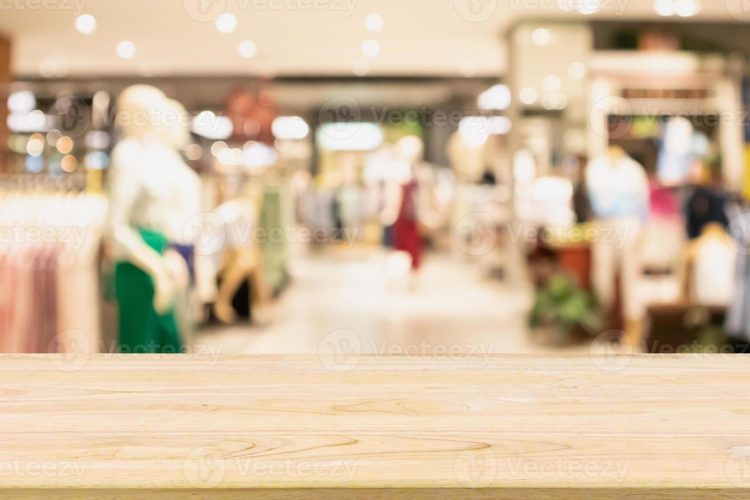 Empty wood table with woman fashionable boutique clothing store window display in shopping mall photo