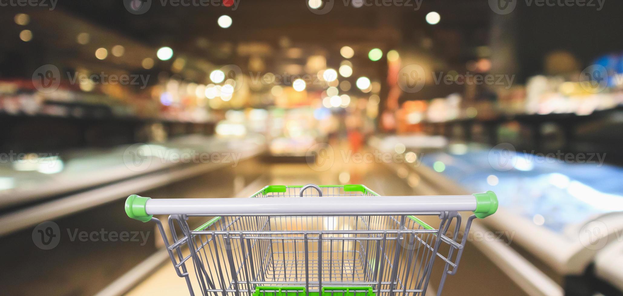 Empty green shopping cart with abstract supermarket aisle interior blurred defocused background with colorful bokeh light photo