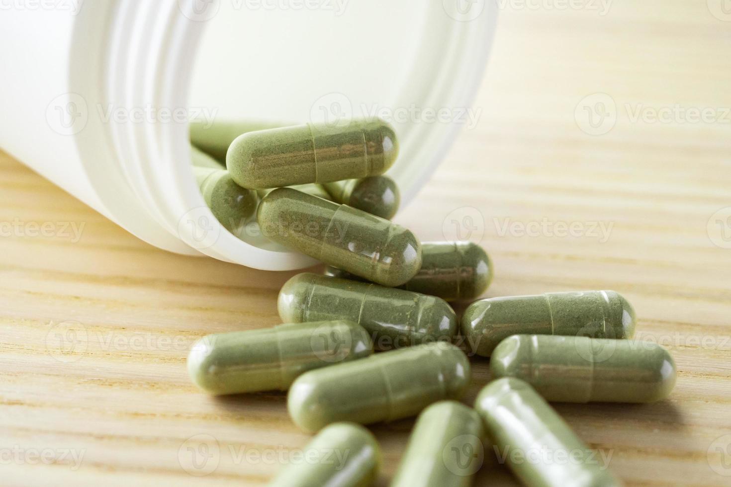 Herbal medicine capsules with bottle on wood table photo