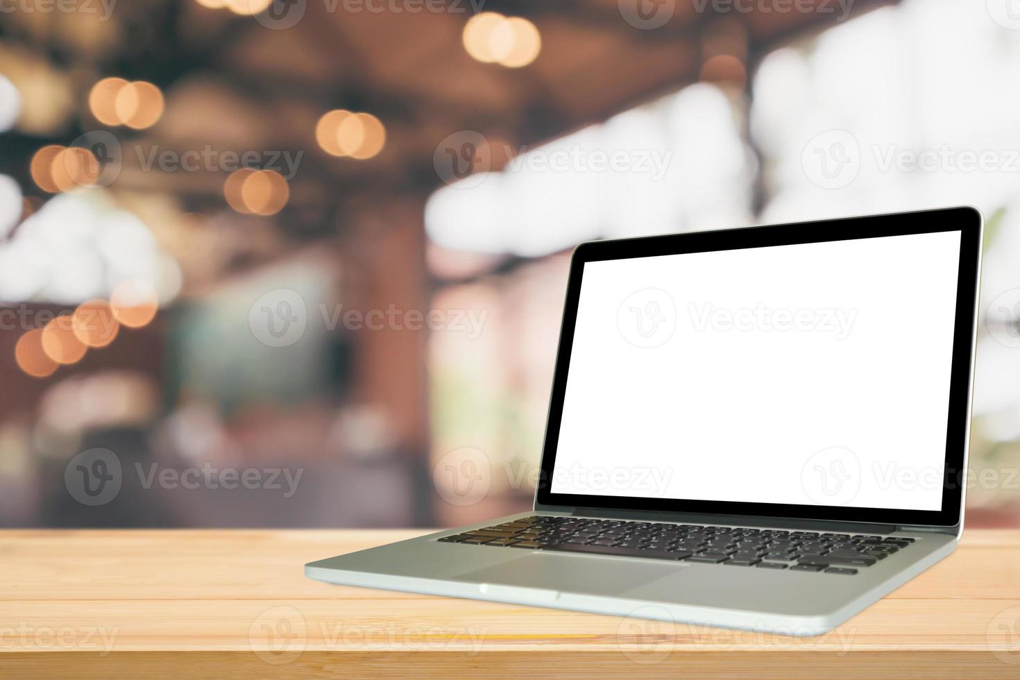 Blank white screen laptop computer on wood table top with cafe restaurant abstract bokeh light defocused blur background photo