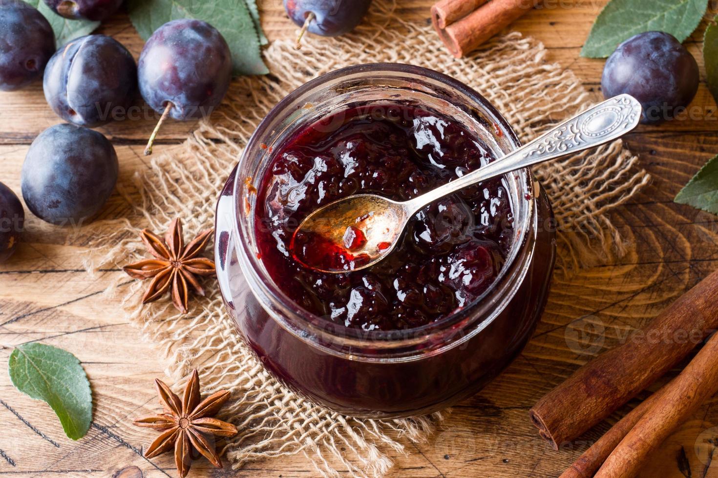 Plum jam in a glass jar. Fresh plum fruit on a wooden table. photo