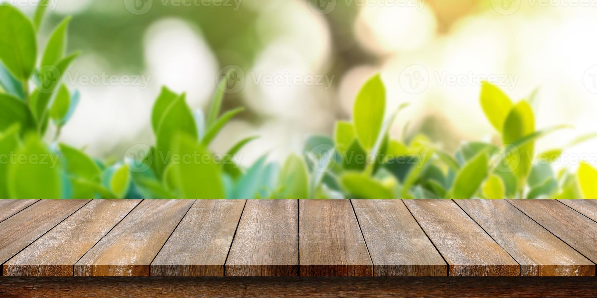 Empty of wooden table top with blurry green leaf and bokeh background. For montage product display or design key visual layouts. photo